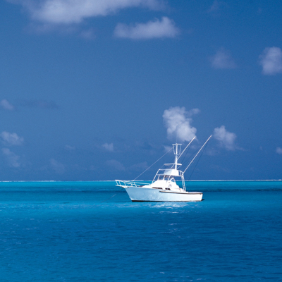 small white yacht floating off in the distance over clear blue waters and under a clear blue sky.